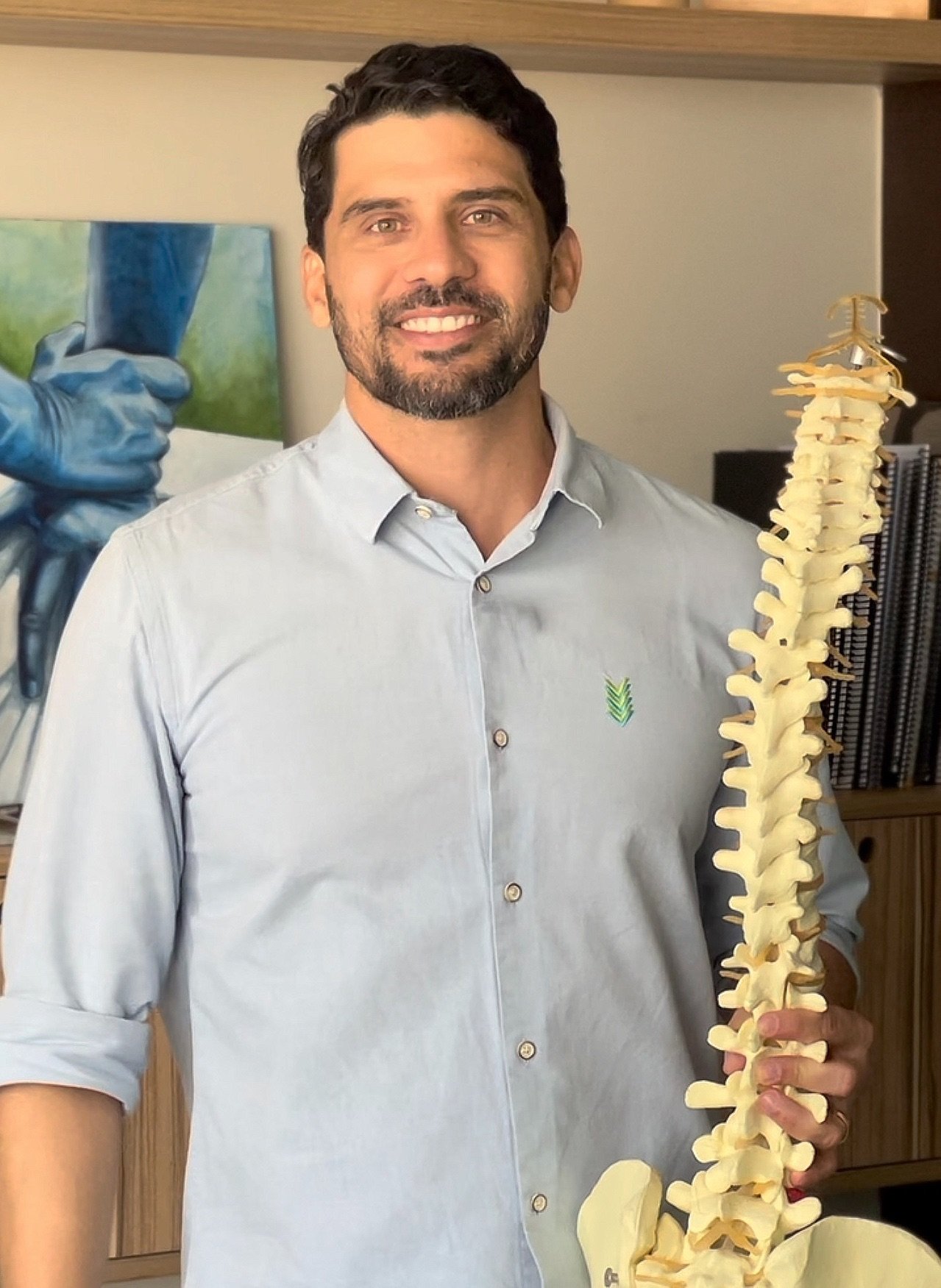 Dr. Lucas Lopes com modelo anatômico da coluna na clínica Go Quiro